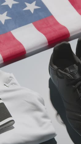 Vertical-Video-Studio-Still-Life-Shot-Of-Football-Soccer-Boots-American-Flag-Shirt-And-Shorts-And-Captains-Armband-